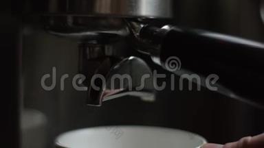 在杯子里倒入专业机器的咖啡流。 咖啡师制作<strong>双倍</strong>浓缩咖啡，使用过滤器支架。 流动
